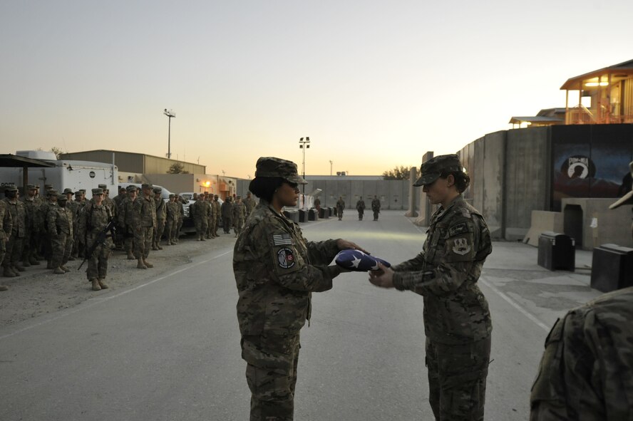 U.S. Air Force Senior Airman Monica Littles, a member of the base honor guard team, receives the flag from fellow honor guard member, U.S. Air Force Staff Sgt. Cara Caldarelli, during a retreat ceremony Nov. 11, 2014 at Bagram Airfield, Afghanistan. The ceremony was held in honor of veterans, both past and present. (U.S. Air Force photo by Capt. Jennifer Bosco/released)