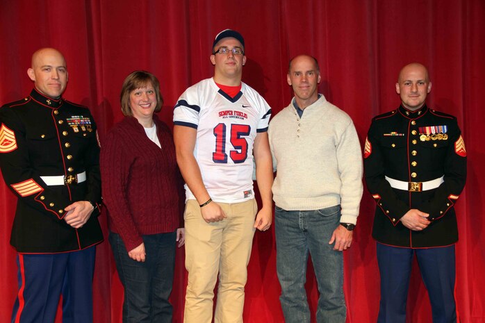 Grant Schmidt, an Offensive Tackle living in Sioux Falls, S.D. attending Roosevelt High School, his parents, and Marine recruiters from Sioux Falls, pose for a picture, November 26. Schmidt was selected to play in the Marine Corps' Semper Fidelis All-American Bowl coming up this January. This rare opportunity is awarded to only those who the Marine Corps has determined best represent the core values of honor, courage and commitment. 