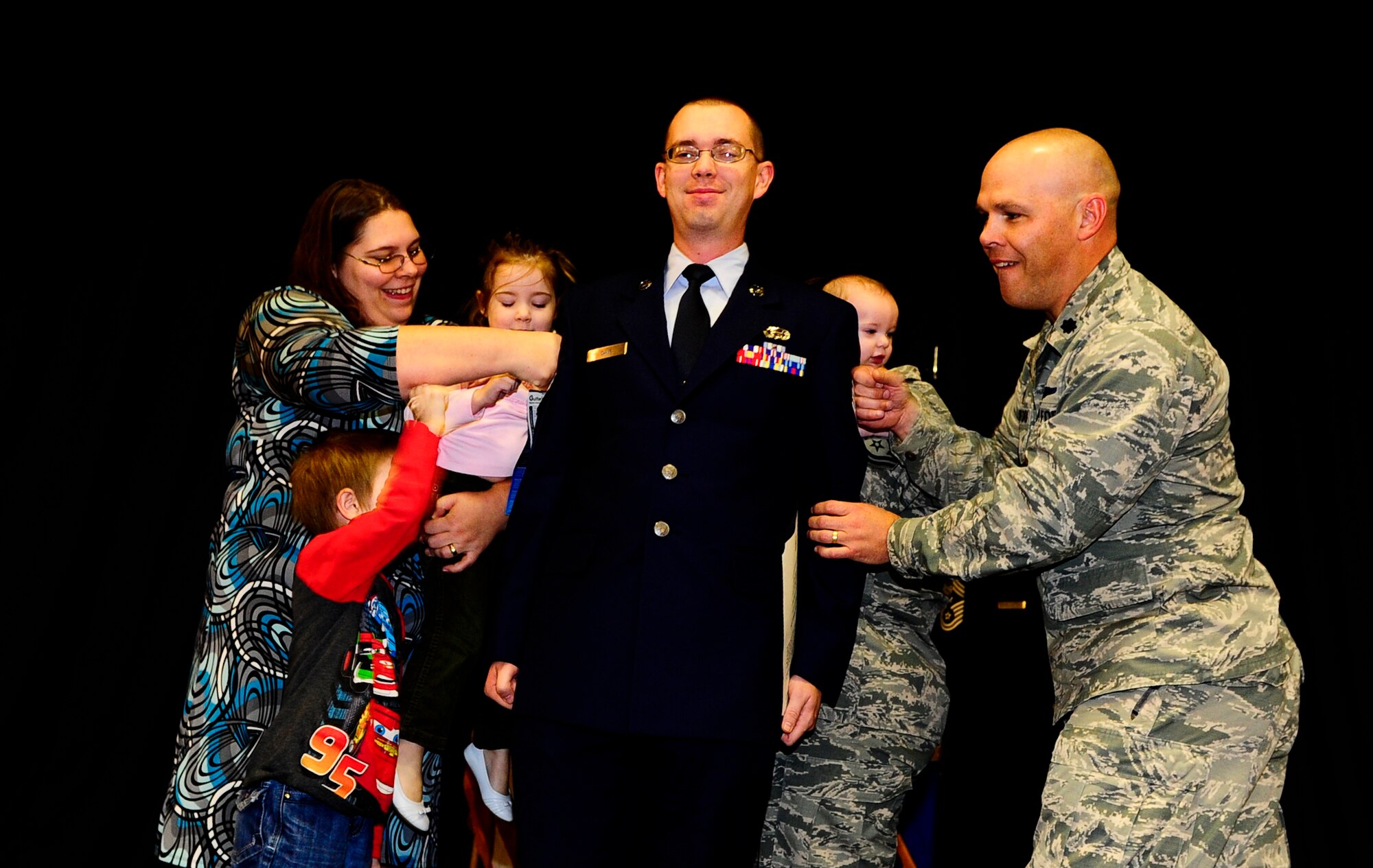 Senior Airman Jonathan Daw’s leadership and family tack on his new Staff Sgt. stripes at an NCO-induction ceremony on Hurlburt Field, Fla., Nov. 26, 2014. An NCO-Induction ceremony is a time-honored tradition of welcoming the newest military leaders. (U.S. Air Force photo/Senior Airman Christopher Callaway)