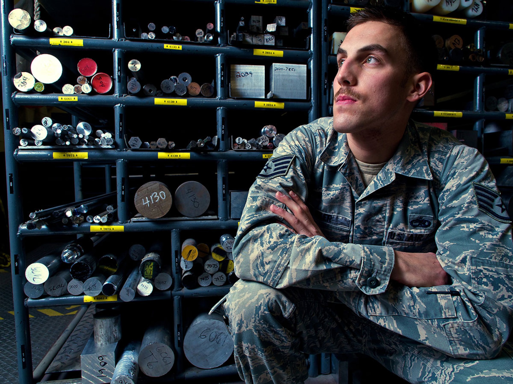 Air Force Staff Sgt. Dan Baker, an aircraft metals technician assigned to 3rd Maintenance Squadron’s Fabrication Flight, is framed by billets of different metals and materials. Baker is a native of Lancaster, Penn. (U.S. Air Force photo/David Bedard)    