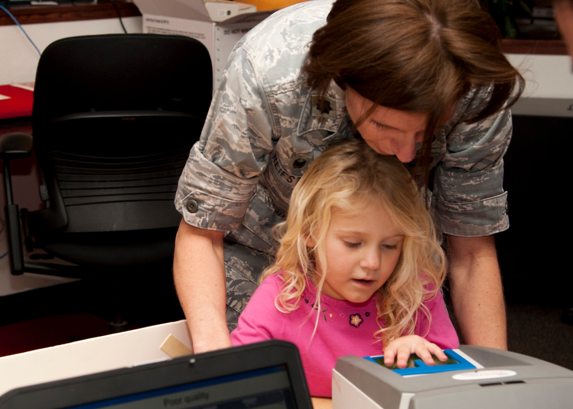 PETERSON AIR FORCE BASE, Colo. - Lt. Col. Laurinda Reifsteck, AFOSI 8th Field Investigations Squadron commander, helps her daughter, Brianna, get her fingerprints taken for an emergency identification kit during Operation Safe Kids at the RP Lee Youth Center, Nov. 20, 2014. Operation Safe Kids is a program by the U.S. Secret Service where parents are provided identification kits of their children’s basic information, photo and fingerprints. If the child goes missing the parents can quickly provide the information to law enforcement agencies. (U.S. Air Force photo by Senior Airman Tiffany DeNault)