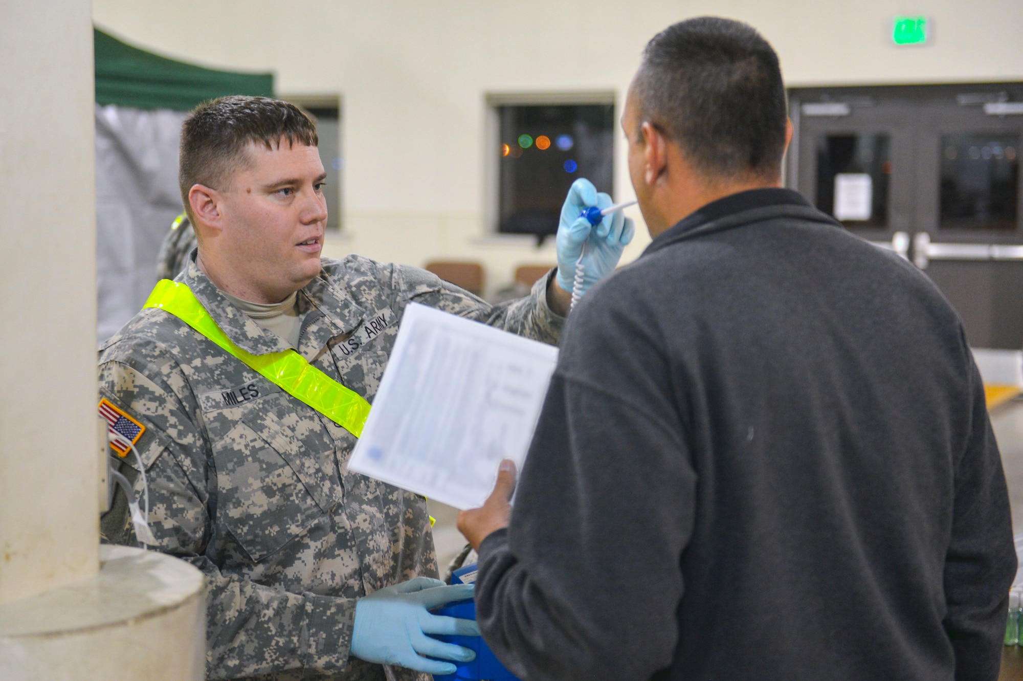 Staff Sgt. John Miles, Madigan Army Medical Center NCO in charge of active duty services, takes the temperature of a returning service member returning from West Africa after supporting Operation United Assistance Nov. 25, 2014, at Joint Base Lewis-McChord, Wash. The 16 joint service members will undergo the DoD’s 21-day controlled monitoring at JBLM after returning from West Africa. (U.S. Air Force photo/Staff Sgt. Russ Jackson)