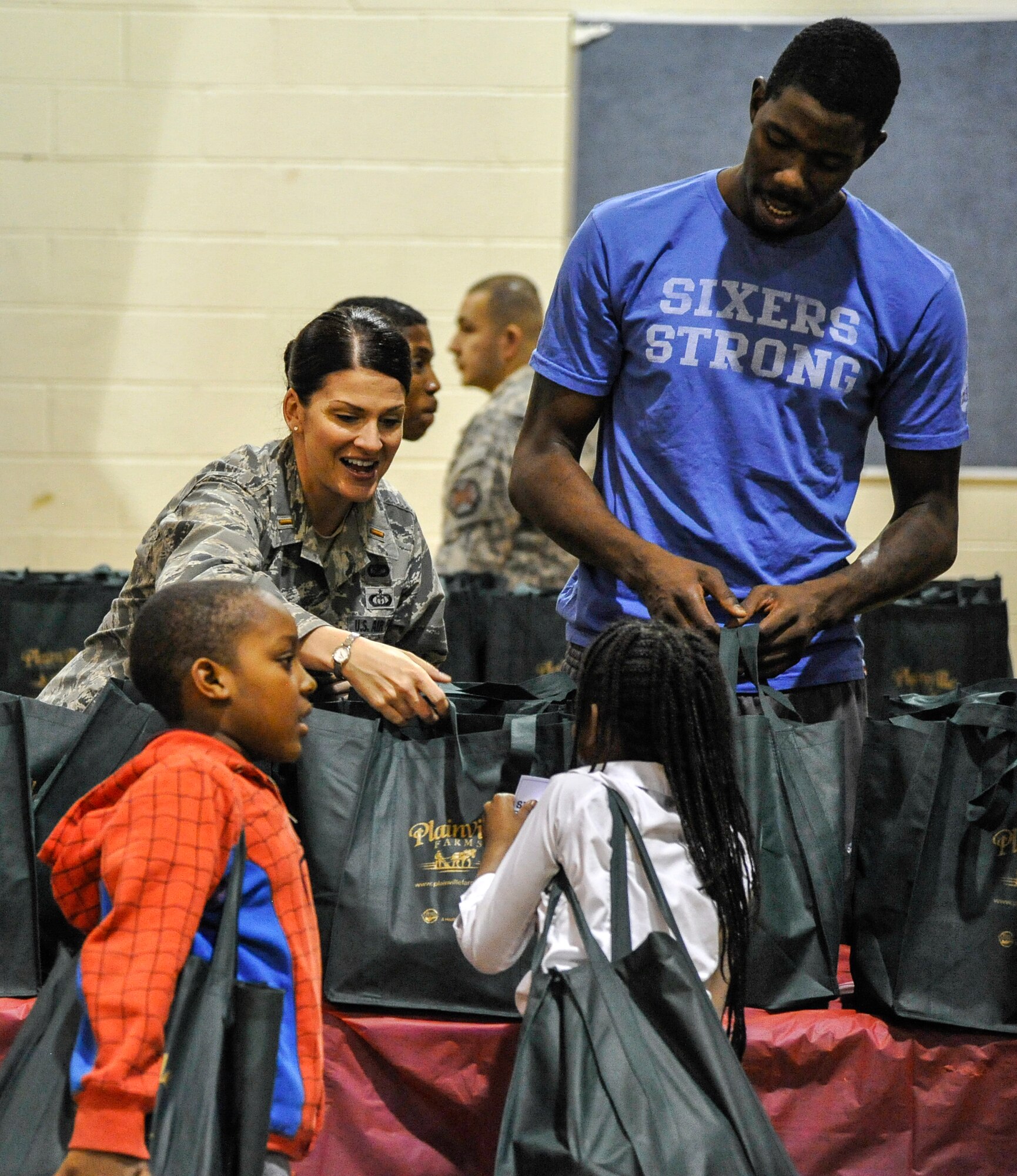 U.S. Air Force 2nd Lt. Carrie Volpe and Philadelphia 76ers center Henry Sims hand out turkeys during an event to help under privileged families at the Wissahickon Boys and Girls Club in Philadelphia Nov. 25, 2014. Service members from Joint Base McGuire-Dix-Lakehurst, New Jersey, and basketball players from the Sixers teamed up to hand out 300 turkeys to families in the area for the holiday season. (U.S. Air Force photo by Staff Sgt. Scott Saldukas/Released)
