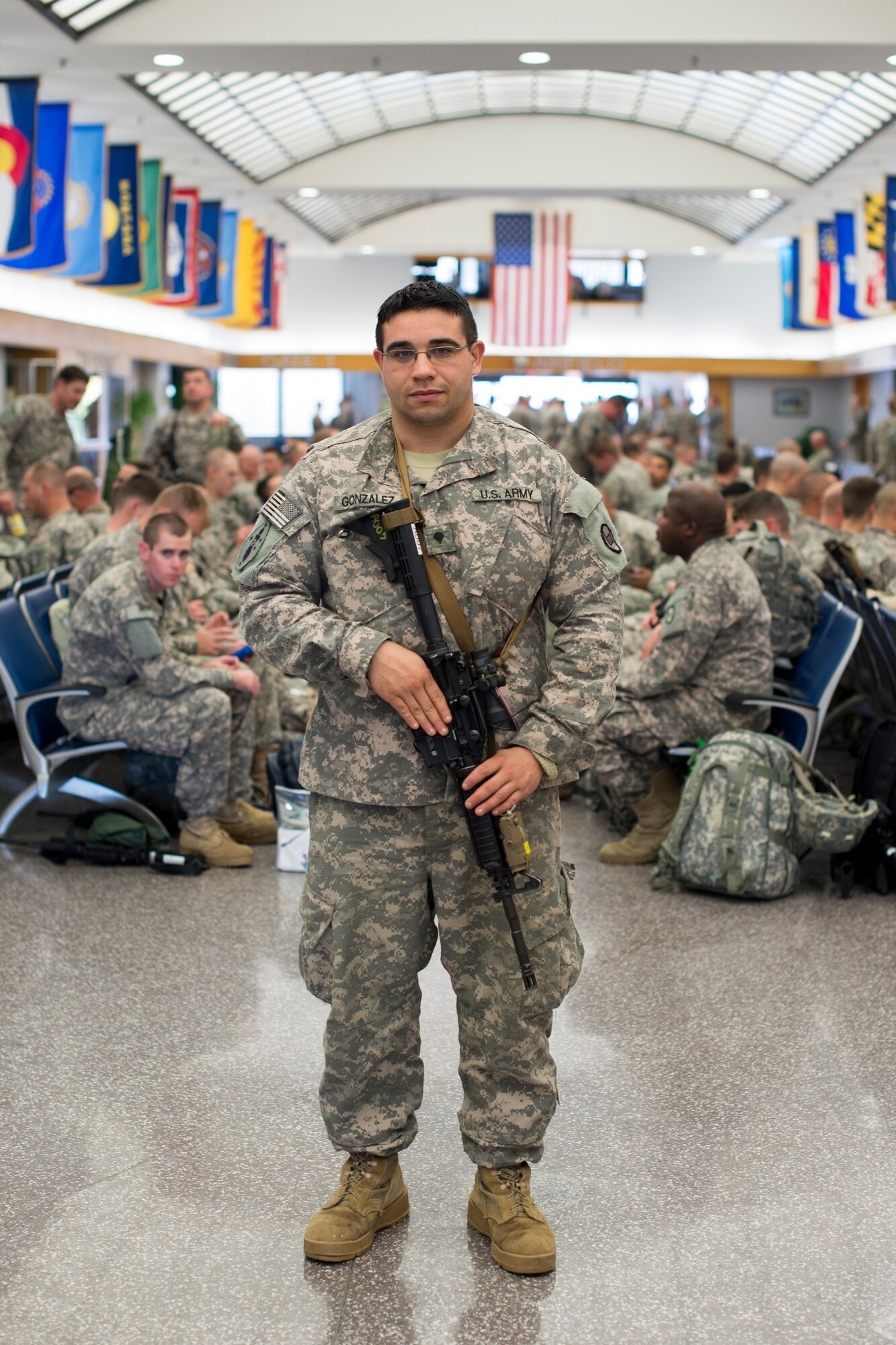 Spc. Joseph Gonzalez, an infantryman with A Company, 1-120th Infantry Regiment, stands in the terminal at Joint Base McGuire-Dix-Lakehurst, N.J., Nov. 23, 2014, waiting to board a plane to the CENTCOM region for a deployment in support of Operation Spartan Shield. Gonzalez joined the North Carolina National Guard after a six-year break in service where he previously spent four years in the Marine Corps. (U.S. Army National Guard Photo by Staff Sgt. Mary Junell / Released)