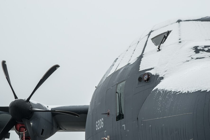 92nd Aircraft Maintenance Squadron Airmen begin to clear snow form a C-130J Super Hercules for preflight inspections and de-icing Nov. 20, 2014 at Fairchild Air Force Base, Wash. The aircraft is from Kirkland AFB, New Mexico and was flown over the Fairchild runway as part of a survival evasion resistance escape (SERE) High Altitude Low Opening (HALO) parachute training the previous day.(U.S. Air Force photo/Staff Sgt. Alexandre Montes)