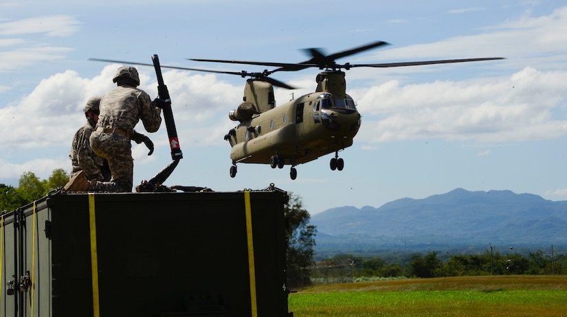 U.S. Army Spcs. Jack Wood and David Swain, assigned to the Army Forces Battalion, prepare to attach a container to a CH-47 Chinook during air load and fly-away training on Soto Cano Air Base, Honduras, Nov. 25, 2014.  The cargo was delivered to the U. S. Southern Command Situational Assessment Team at the Warrior Ramp for employment in the day’s training event.  During the training members of the S-SAT received training on setting up a Pre-Positioned Expeditionary Assistance Kit to help prepare the team respond efficiently to humanitarian assistance and disaster response situations throughout U.S. Southern Command’s area of responsibility.  The PEAK is designed to provide sustainable, essential services in the first 72 hours after a disaster event. The training focused on S-SAT familiarization, hands on training and a fly-away event between JTF-Bravo S-SAT personnel, Army Forces Battalion, and 1-228th Aviation Regiment in preparation for an upcoming exercise.  (U.S. Air Force photo/Tech. Sgt. Heather Redman)