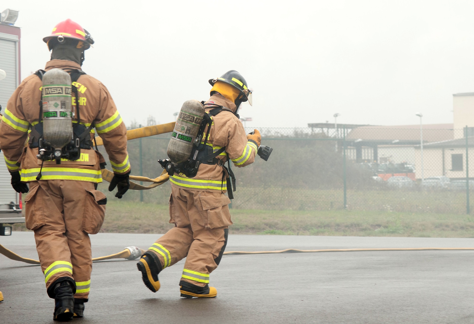 Chief Master Sgt. Frank H. Batten III, 86th Airlift Wing command chief, pulls a hose from a fire engine at Ramstein Air Base, Germany, Nov. 19, 2014. Batten participated in a burn house training scenario alongside Brig. Gen. Patrick X. Mordente, 86th AW commander, and firefighters assigned to the 86th Civil Engineer Squadron. The burn house training allows firefighters to experience battling a live fire in a controlled environment. (U.S. Air Force photo/Senior Airman Timothy Moore)