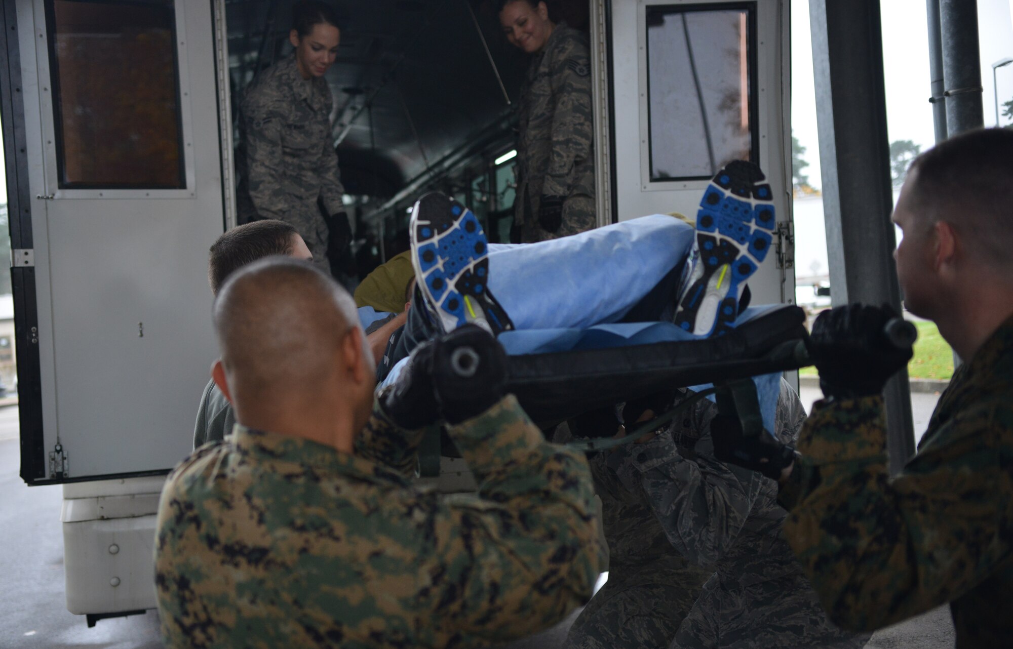 A group of Airmen and Marines load a patient onto a medical bus to take them to the flightline on Ramstein Air Base, Germany, Nov. 20, 2014. Contingency Aeromedical Staging Facility members wait to get the wheels up call before ending their day. (U.S. Air Force photo/Senior Airman Hailey Haux)