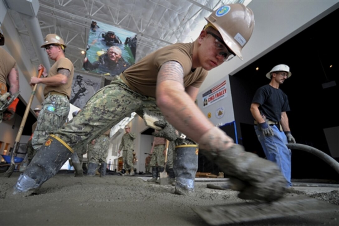 Navy Seaman Brandon Schwing levels the concrete at the U.S. Navy Seabee Museum in Port Hueneme, Calif., Nov. 20, 2014. Schwing is a builder assigned to Naval Mobile Construction Battalion 3.  