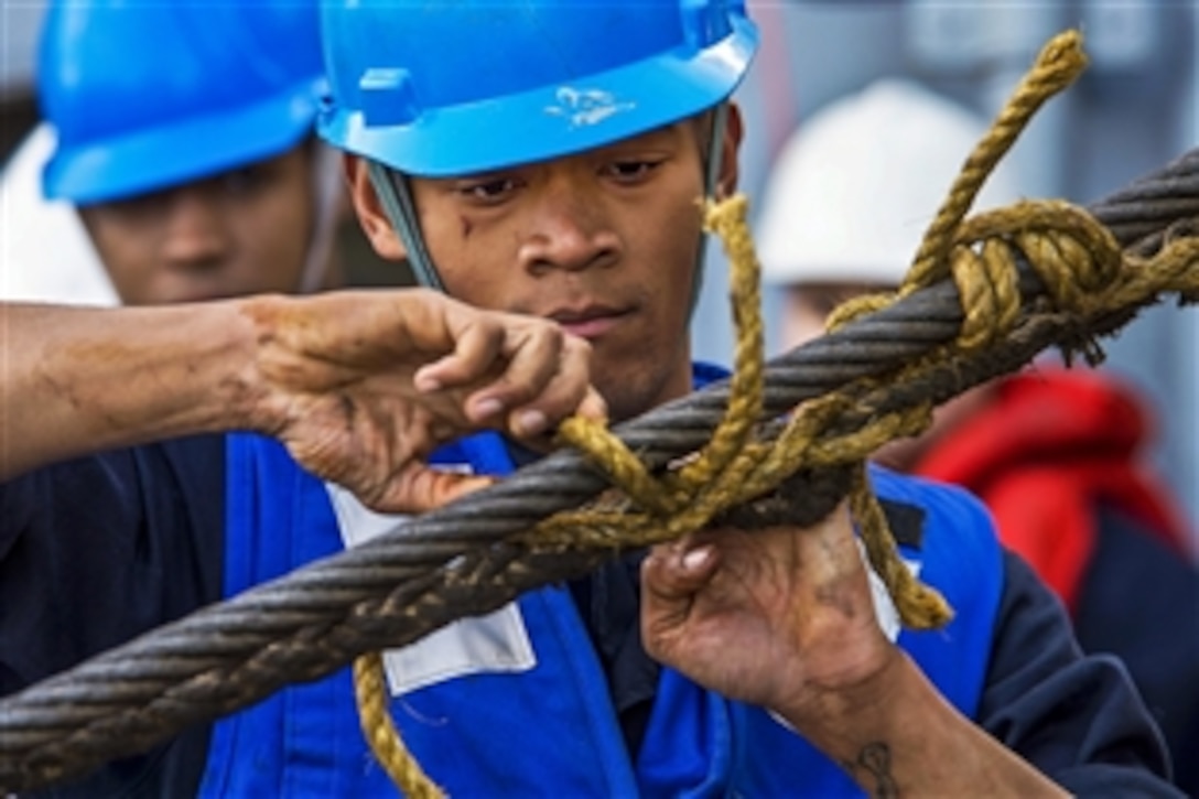 U.S. Navy Seaman Auche Robertchalmers pulls the messenger line free of the span wire during a replenishment on the guided-missile destroyer USS Cole in the Mediterranean Sea, Nov. 23, 2014. The destroyer is conducting naval operations in the U.S. 6th Fleet area of responsibility to support U.S. national security interests in Europe. 