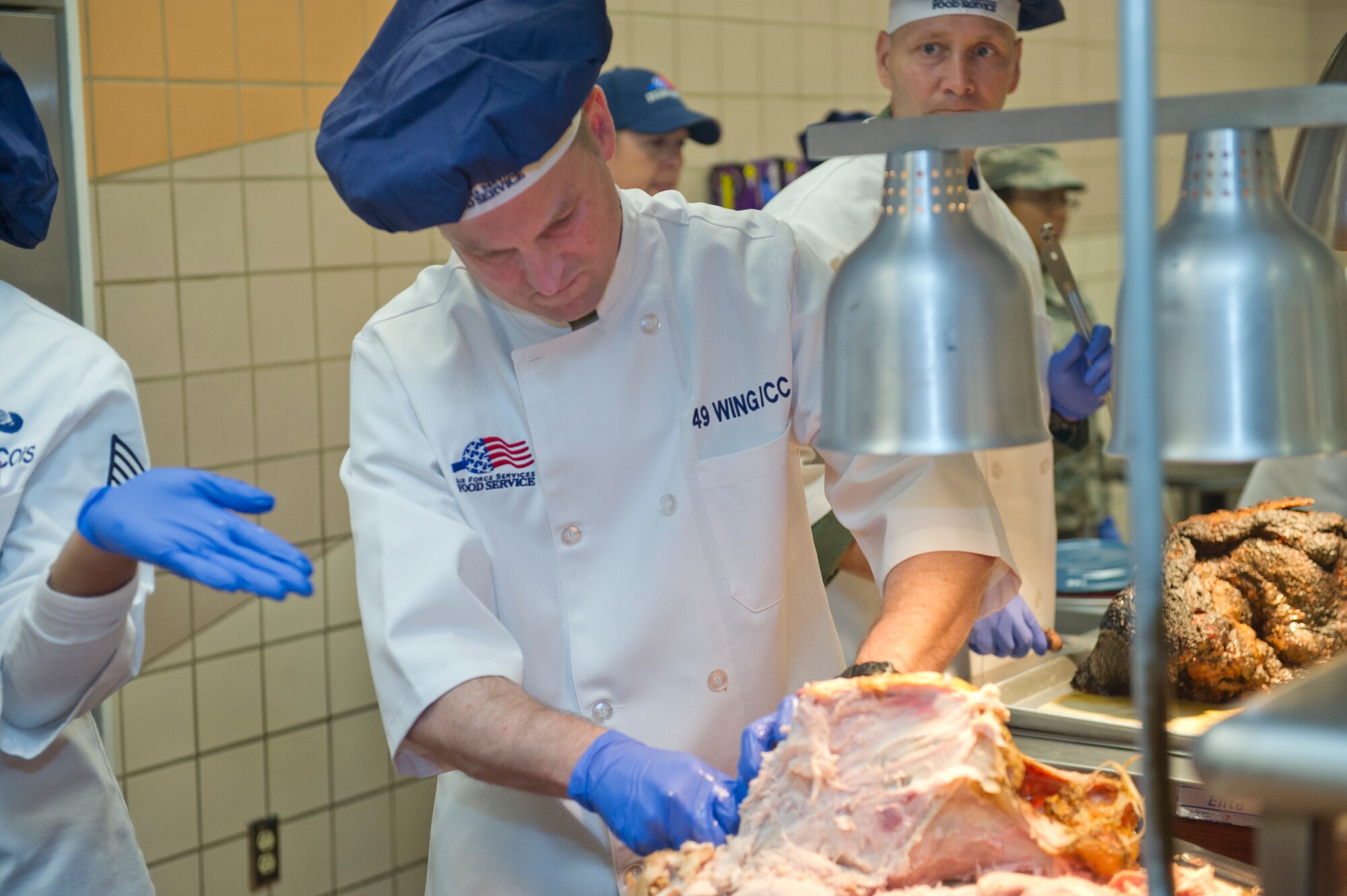Colonel Robert Kiebler, 49th Wing commander, spends Thanksgiving carving turkey to be served at Shifting Sands Dining Facility at Holloman Air Force Base, N.M., Nov. 27. Senior leadership from around base gathers annually in an effort to ensure that every Airman from Holloman AFB gets to have a Thanksgiving meal as a part of the Air Force Family. (U.S. Air Force Photo by Airman 1st Class Chase Cannon/Released)