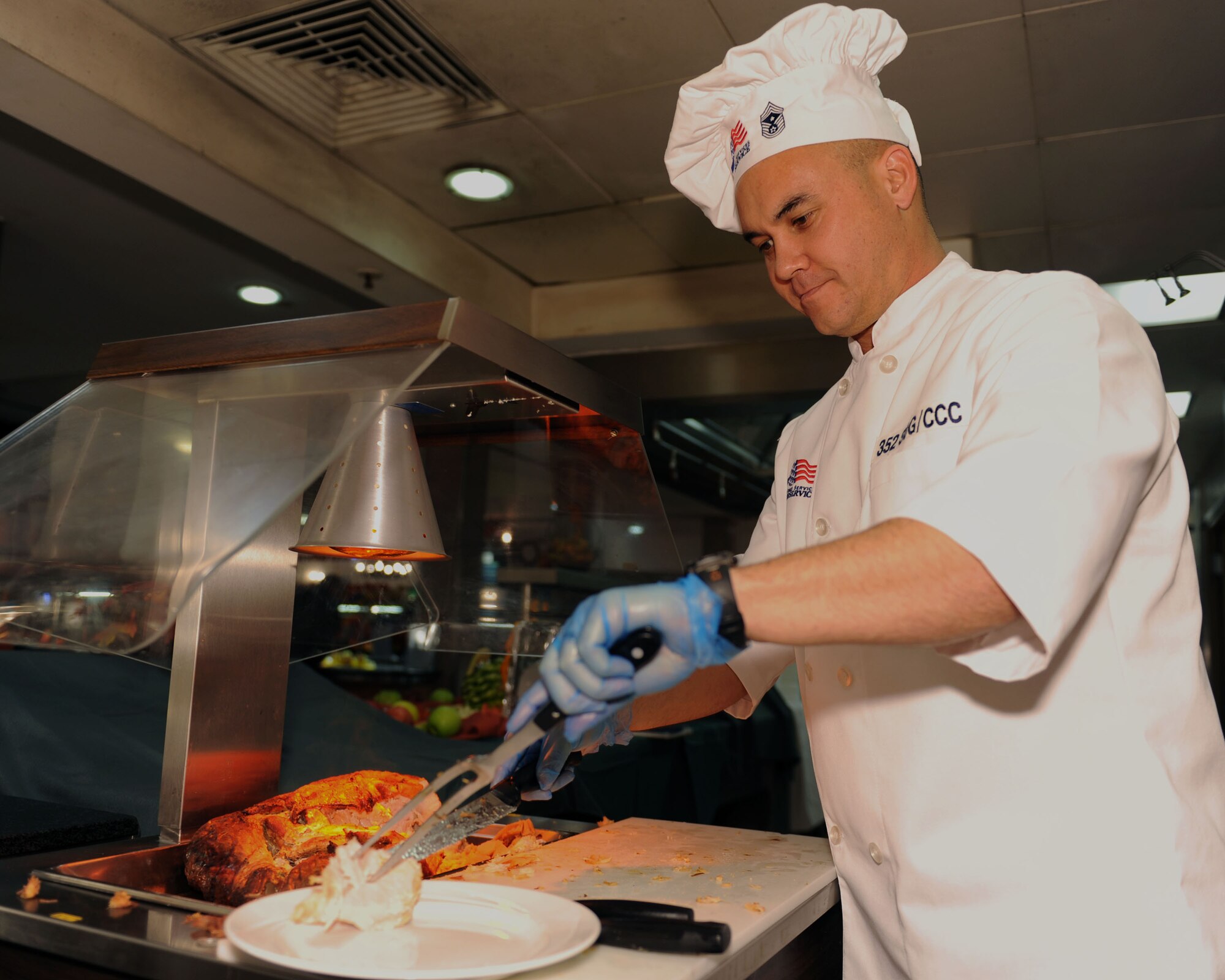 U.S. Air Force Chief Master Sgt. Robert Gibbons, 352nd Special Operations Group command chief, serves Thanksgiving turkey Nov. 27, 2014, at the Gateway Dining Facility at RAF Mildenhall, England. Team Mildenhall leadership joined with the dining facility staff to provide Airmen the opportunity to enjoy Thanksgiving away from home. (U.S. Air Force photo by Airman 1st Class Preston Webb/Released)