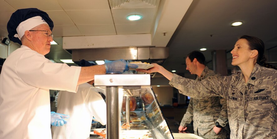 U.S. Air Force Col. Matthew Powell, Joint Special Operations Air Component Europe vice commander, left, serves Thanksgiving lunch to U.S. Air Force Lt. Col. Heather Baldwin, 100th Operations Support Squadron commander, right,  Nov. 27, 2014, at the Gateway Dining Facility at RAF Mildenhall, England. Team Mildenhall leadership joined with the dining facility staff to provide Airmen the opportunity to enjoy Thanksgiving away from home. (U.S. Air Force photo by Airman 1st Class Preston Webb/Released)