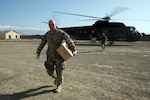U.S. Army Sgt. 1st Class Teddy Gribbins retrieves the mail from a helicopter at Combat Outpost Dand Patan, Afghanistan, Feb. 18, 2010.
