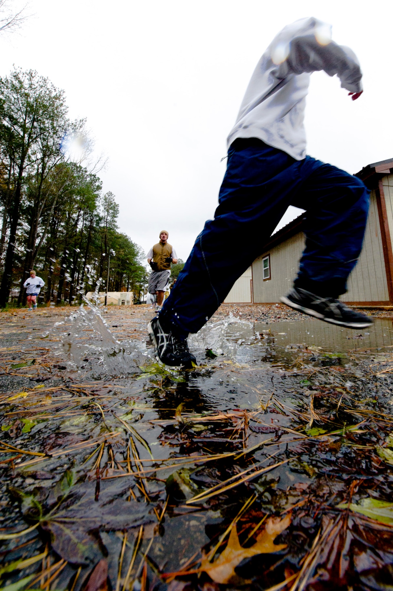 A U.S. Air Force Airman steps on a puddle as he runs while taking part in the Thanksgiving Turkey Trot 3K run at the Langley Transit Center as part of their Thanksgiving celebration at Joint Base Langley-Eustis, Va., during their controlled monitoring period, Nov. 27, 2014. The members recently returned from Liberia supporting Operation United Assistance, a Department of Defense operation in Liberia to provide logistics, training and engineering support to U.S. Agency for International Development-led efforts to contain the Ebola virus outbreak in West Africa. (U.S. Air Force photo by Staff Sgt. Gustavo Gonzalez/Released)