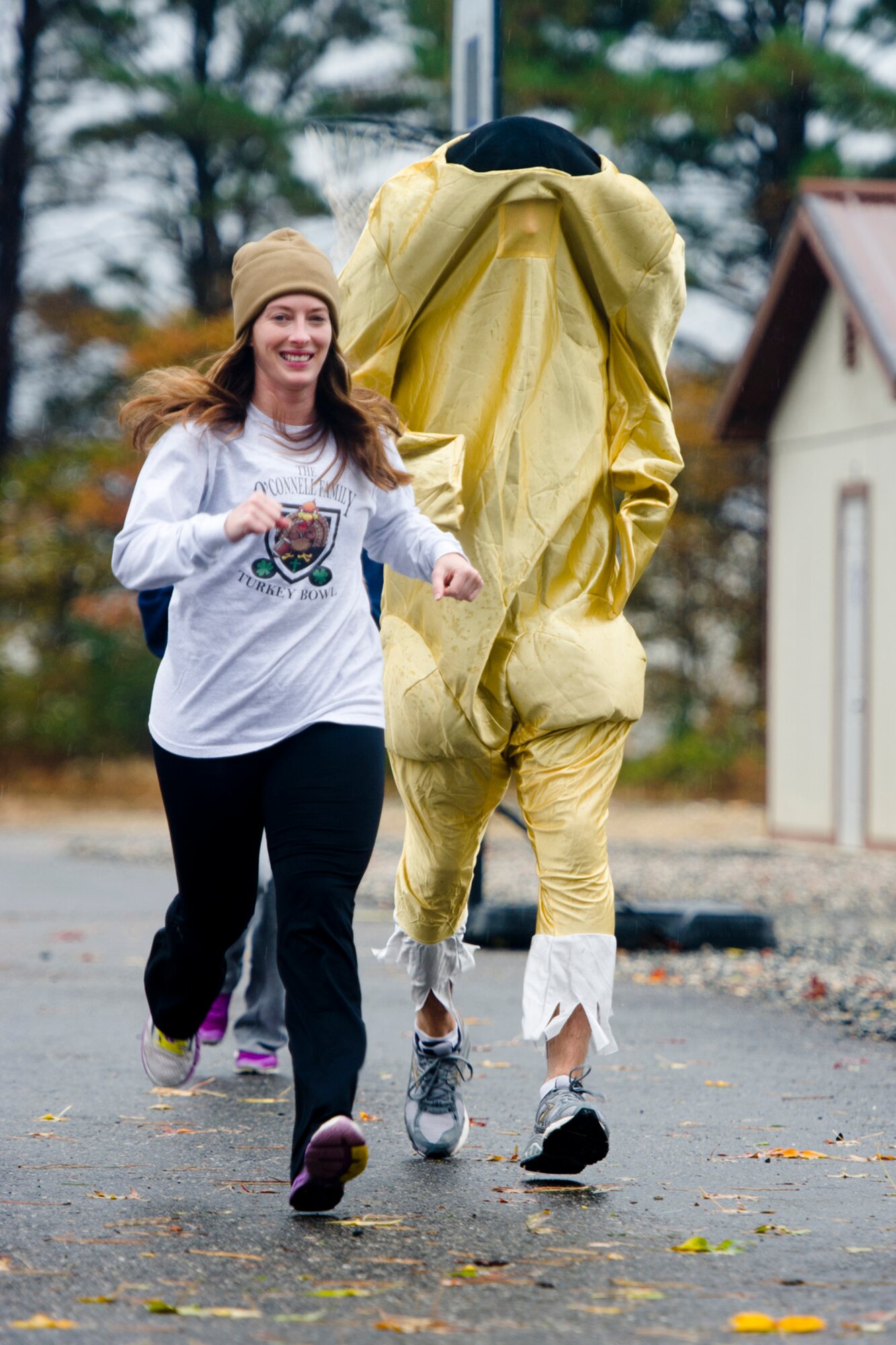U.S. Navy Lt.j.g. Kristy Gregorich runs next to U.S. Air Force Lt. Col. Andrew Venne, dressed in a turkey costume, as they take part in the Thanksgiving Turkey Trot 3K run at the Langley Transit Center as part of their Thanksgiving celebration at Joint Base Langley-Eustis, Va., during their controlled monitoring period, Nov. 27, 2014. The members recently returned from Liberia supporting Operation United Assistance, a Department of Defense operation in Liberia to provide logistics, training and engineering support to U.S. Agency for International Development-led efforts to contain the Ebola virus outbreak in West Africa. (U.S. Air Force photo by Staff Sgt. Gustavo Gonzalez/Released)