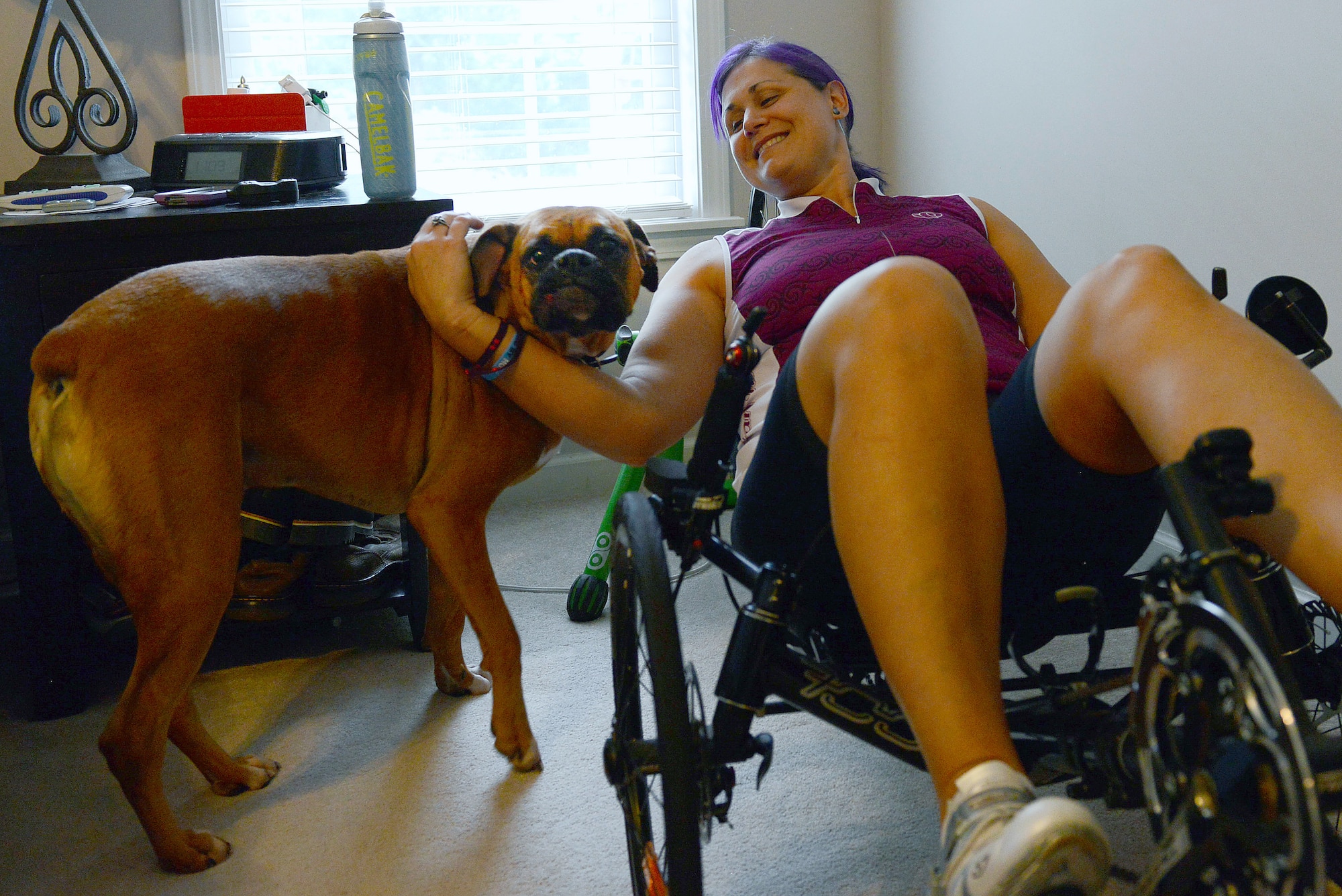 Retired Maj. Jen Kyseth trains on her recumbent bike while her dog, Mack, waits by her side Sept. 15, 2014, in Sumter, S.C. Every time Kyseth trains on her bike, Mack is there with her to show support which boosts her motivation. (U.S. Air Force photo/Airman 1st Class Diana M. Cossaboom)