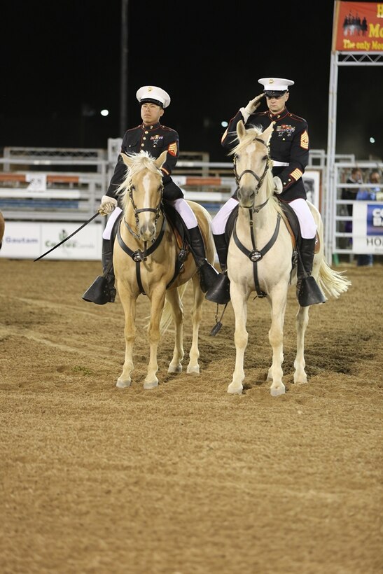 Sergeant Moses Machuca (left), and First Sgt. Edward Kretschmer, stablemen with the Marine Corps Mounted Color Guard on Marine Corps Logistics Base Barstow, Calif., present arms during the 2014 Barstow Rodeo Stampede, Sept. 27 at the stables here. The MCG presented colors to open the rodeo with the 11th Armored Calvary Regiment from National Training Center, Fort Irwin.