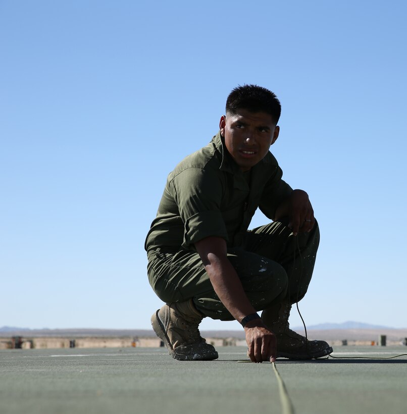 Sgt. Horacio Leyva, runway supervisor, Marine Wing Support Squadron 374, makes sure the number at the end of the expeditionary runway is straight to prepare for painting on the Strategic Expeditionary Landing Field at Camp Wilson, Sept. 29,2014. 40 Marines replaced the worn panels to improve the runway and ensure a safer landing zone for aircraft.