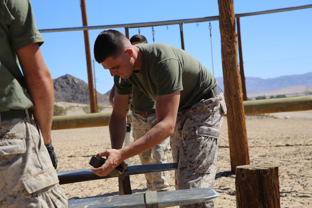 Sgt. Brett Demond, combat engineer, Combat Logistics Battalion 7, harnesses a log to a forklift during renovations of an obstacle course near the East Gym, Monday. The renovations come as a result of unusable obstacles.