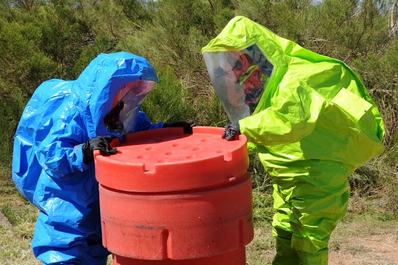U.S. Air Force Senior Airman Constance Moore and Staff Sgt. Ashley Jordan, 355th Aerospace Medicine Squadron bioenvironmental engineering technicians, place a leaking 55 gallon drum inside an overpack to prevent further contamination during a Multi-Agency HAZMAT Exercise at Davis-Monthan Air Force Base, Ariz., Sept. 29, 2014. The objective of the exercise was to secure the scene, minimize environmental impact, establish hazard zones and enter the hot zone in appropriate personnel protective equipment to determine the unknown material and mitigate the incident. (U.S. Air Force photo by Airman 1st Class Cheyenne Morigeau/Released)