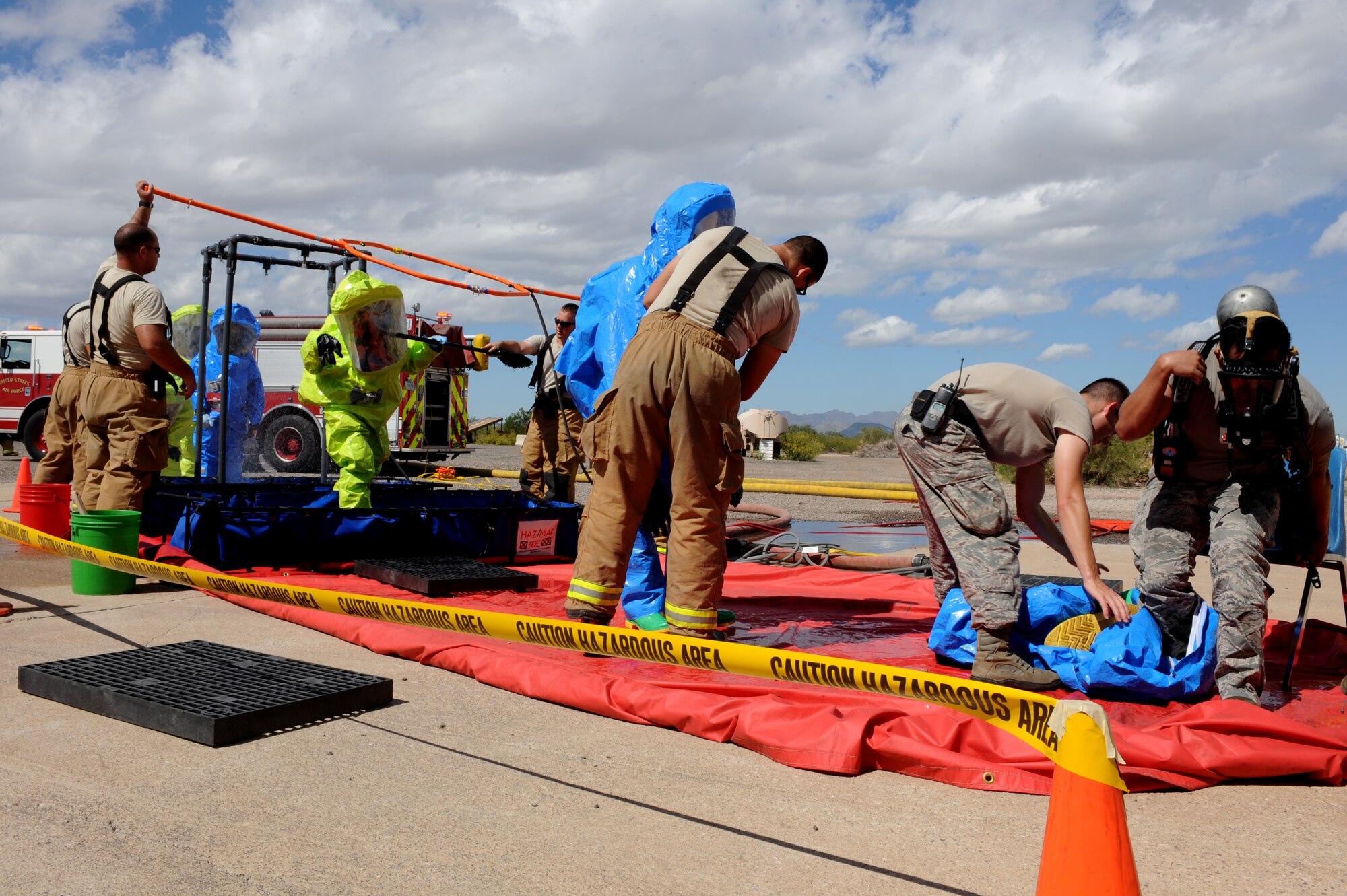 Responders from the Bioenvironmental Engineering and Emergency Management flights proceed through a decontamination zone following operations in a simulated contaminated area at Davis-Monthan Air Force Base, Ariz., Sept. 29, 2014.  Decontamination is an essential element of handling hazardous materials because it minimizes the spread of contaminants to both personnel and equipment. This training showcased the expertise and resources that are available to D-M leadership in the event of a real-world incident involving hazardous materials.  (U.S. Air Force photo by Airman 1st Class Cheyenne Morigeau/Released)