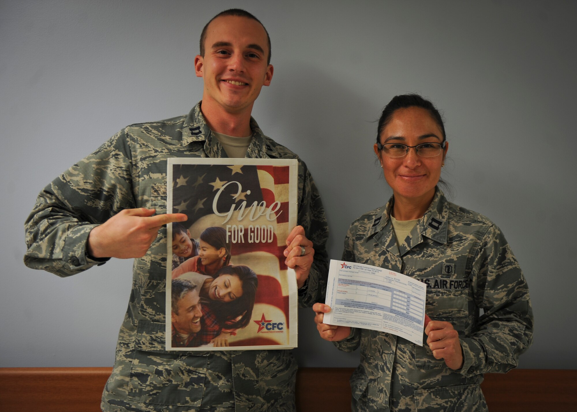 Capt. Andrew York (left), 99th Security Forces Squadron operations officer, and Capt. Gabriela Daniels, 99th Medical Operations Squadron physical therapist, displays a booklet and pledge form for the 2014 Combined Federal Campaign at Nellis Air Force Base, Nev., Sept. 29, 2014. The CFC, which will run here from Sept. 2 through Dec. 15, is an opportunity for all federal employees to donate money to a number of non-profit organizations that assist individuals in need. York and Daniels are the installation’s CFC representatives. (U.S. Air Force photo by Airman 1st Class Mikaley Towle)