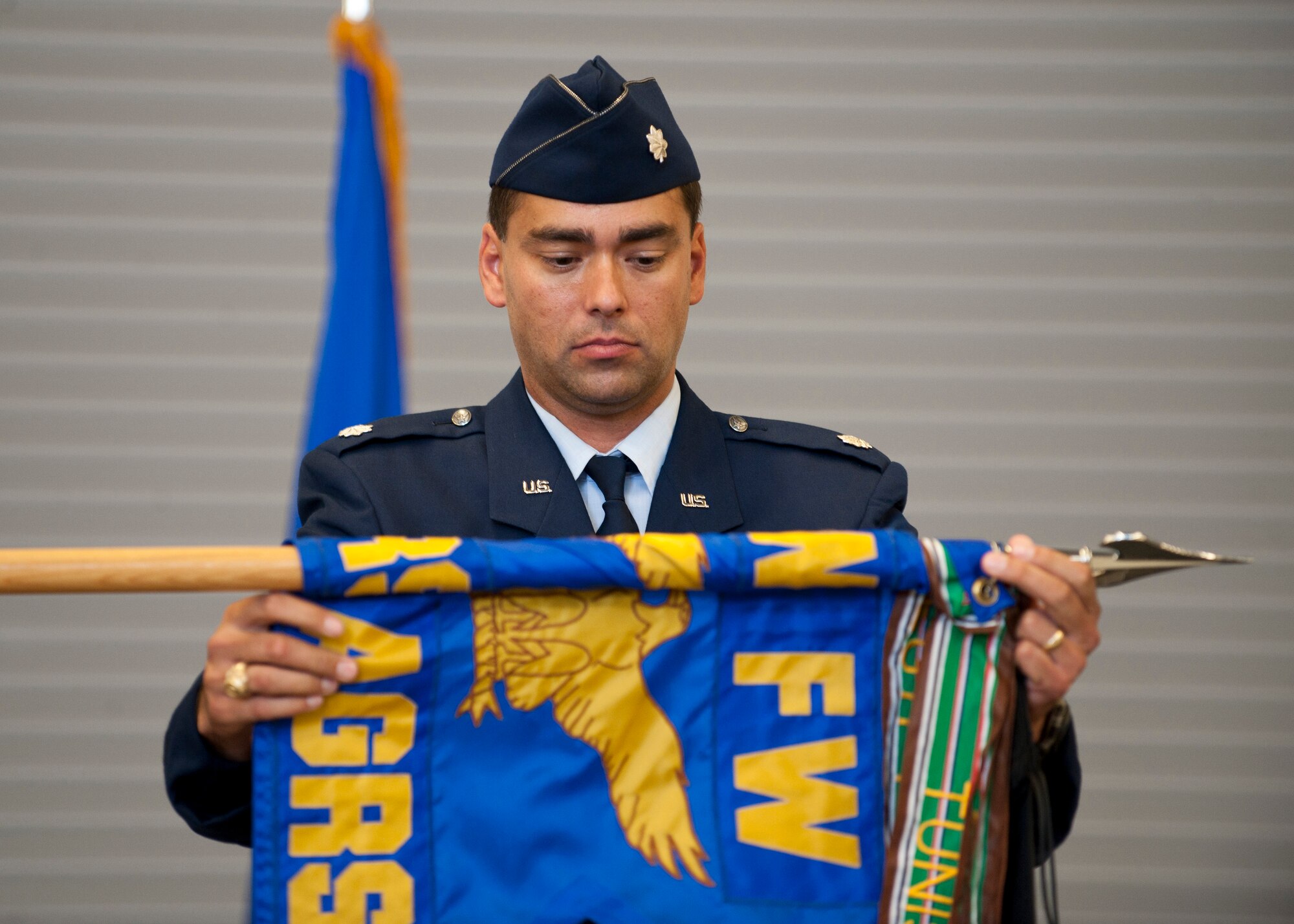 Lt. Col. Gregory Wintill, former commander of the 65th Aggressor Squadron, cases the 65th AGRS flag at the Flanker Aircraft Maintenance Unit at Nellis Air Force Base, Nev., Sept 26, 2014. The 65th AGRS has helped to train thousands of service members by acting in the aggressor role during exercises such as Red Flag, and have also helped to test the capabilities of different aircraft including the F-22 Raptor, F-35 Lightning II, F-15 Eagle, F-16 Fighting Falcon, and F/A-18 Hornet. The mission and responsibilities held by the 65th AGRS will be solely filled by the 64th Aggressor Squadron. The pilots who were assigned to the 65th AGRS will either continue to fly or take another path, depending on what the Air Force requires of them. The F-15s assigned to the 65th AGRS will be reassigned to various Air National Guard Bases. (U.S. Air Force photo by Airman 1st Class Thomas Spangler)