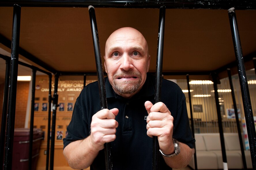Matthew Worden, a PAE transportation manager in the 71st Logistics Readiness Squadron, stands behind bars during the Defenders Association Jail and Bail Sept. 26 in Building 500. Worden spent 142 minutes in the makeshift cell. The 71st Security Forces Squadron “arrested” individuals for one dollar per minute.  The funds raised will support morale and welfare events for SFS Airmen. (U.S. Air Force photo/Staff Sgt. Nancy Falcon)