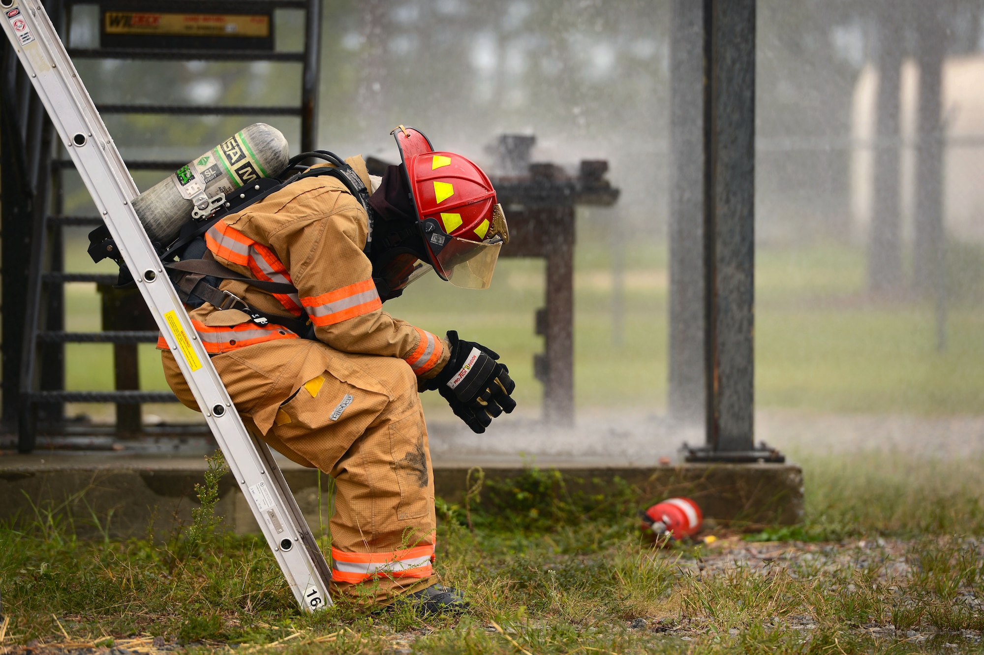 U.S. Air Force Staff Sgt. Micah Cook, 20th Civil Engineer Squadron firefighter, rests on a ladder after participating in live fire structural burn training at Shaw Air Force Base, S.C., Sept. 26, 2014. Due to temperatures that can reach up to 900 degrees in the structural burn tower, Airmen are advised to hydrate and rest after spending large amounts of time in the tower. (U.S. Air Force photo by Airman 1st Class Jensen Stidham/Released) 