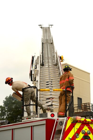 (From left) U.S. Air Force Staff Sgt. Chastin Warner and Senior Airman Adam Hunt, 20th Civil Engineer Squadron firefighters, inspect an aerial ladder during live fire training exercise at Shaw Air Force Base, S.C., Sept. 26, 2014. The two were preparing to lower the ladder near a window on the burn tower to perform a simulated rescue. (U.S. Air Force photo by Airman 1st Class Jensen Stidham/Released) 