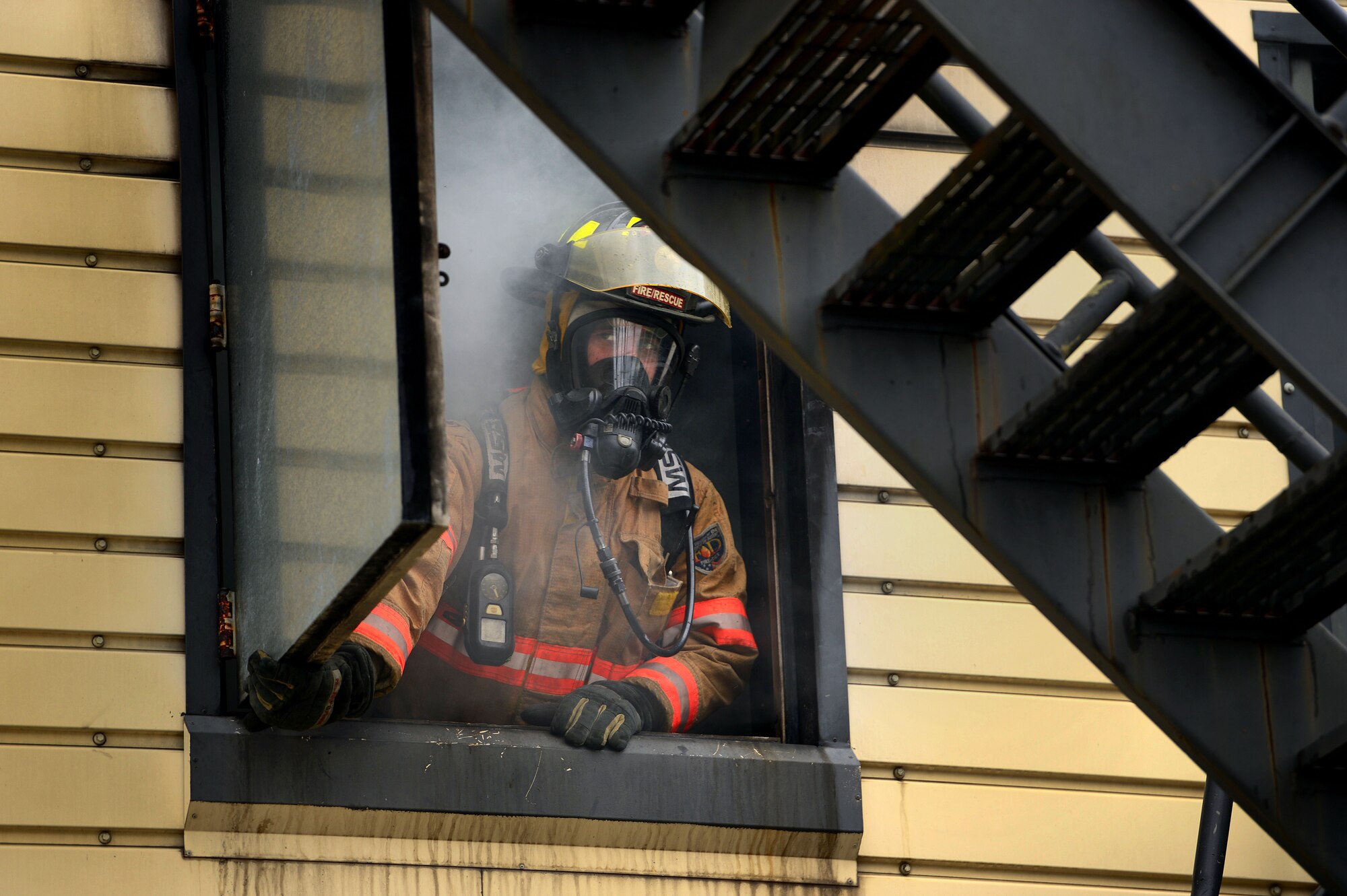 U.S. Air Force Senior Airman Clayton Angeloff, 20th Civil Engineer Squadron firefighter, opens a window on the structural burn tower at Shaw Air Force Base, S.C., Sept. 26, 2014.  Angeloff opened the window for proper ventilation and visibility during a live fire training exercise that consisted of several no-notice scenarios needing to be extinguished. (U.S. Air Force photo by Airman 1st Class Jensen Stidham/Released) 