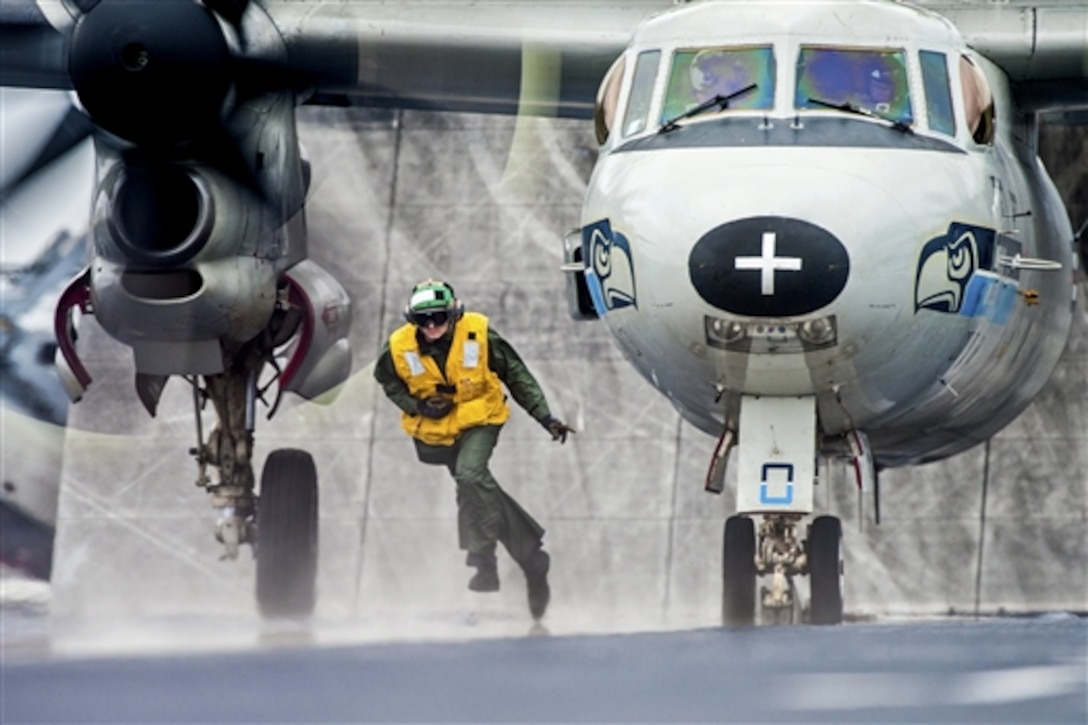 U.S. Navy Seaman Daniel Alt clears the launch path of an E-2C Hawkeye after attaching it to a catapult on the flight deck of the aircraft carrier USS Harry S. Truman in the Atlantic Ocean, Sept. 26, 2014. Alt is an aviation boatswain's mate airman and the Hawkeye is assigned to Airborne Early Warning Squadron 126.