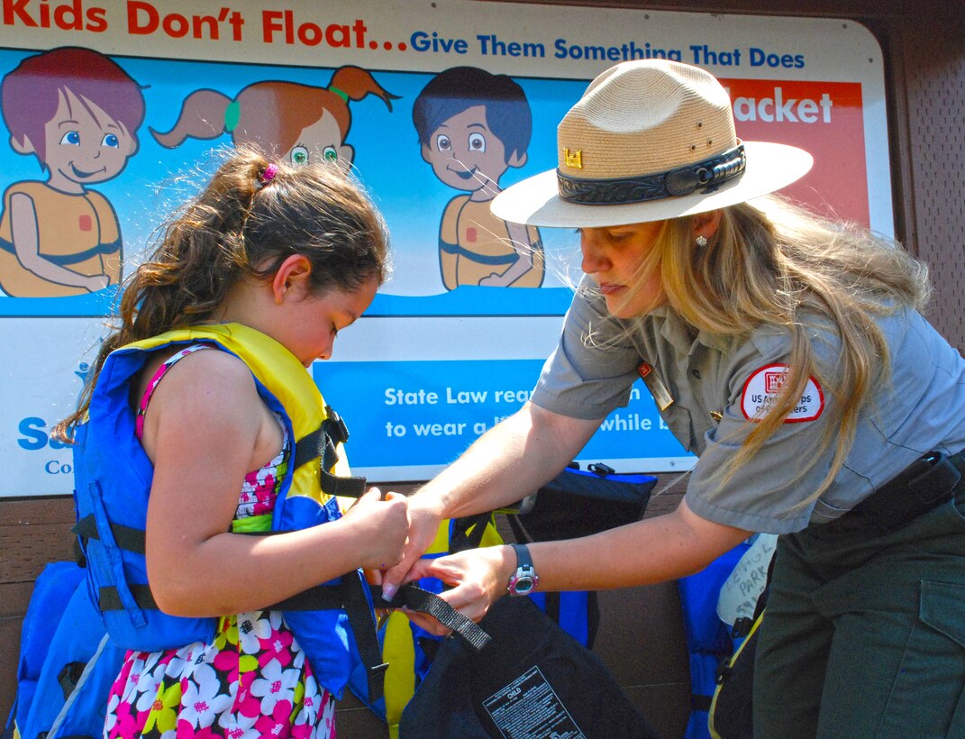 Park Ranger Megan Christianson shows a young visitor to Lepage Park how to fit a life jacket properly. The boat ramp at the park has a life jacket loaner station that provides life jackets for visitors who want to enjoy water recreation there.