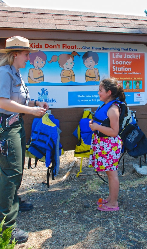 Park Ranger Megan Christianson advises a young visitor to Lepage Park on how to tell if a life jacket fits properly. The boat ramp at the park has a life jacket loaner station to encourage life jacket use even if someone has forgotten to bring one.
