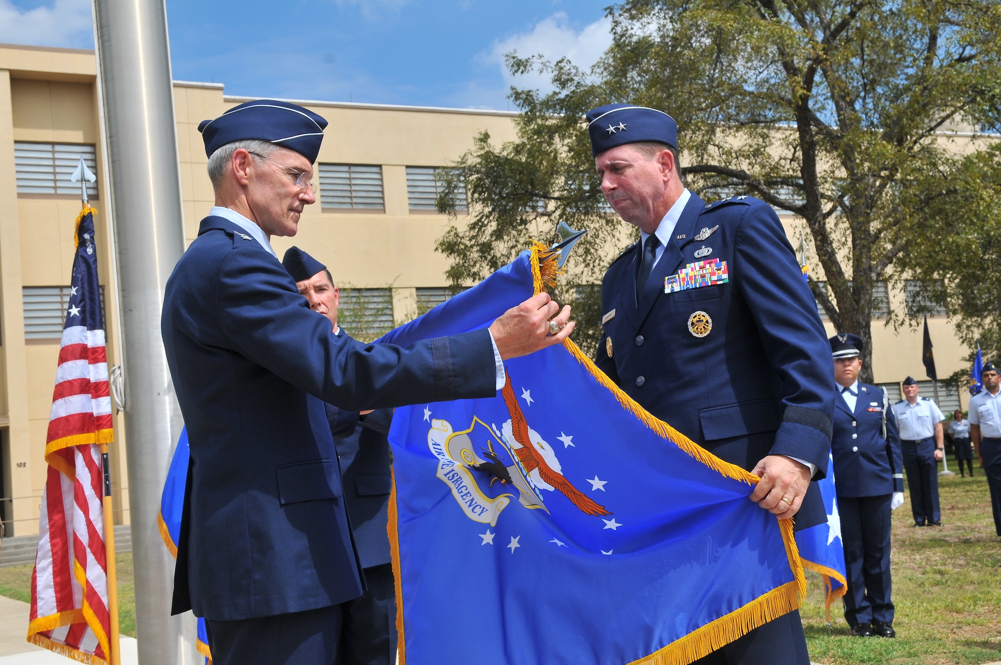 Lt. Gen. Robert Otto, Headquarters Air Force deputy chief of staff, intelligence, surveillance and reconnaissance, left, and Maj. Gen. John Shanahan furl the Air Force ISR Agency flag. Shanahan relinquished command of the agency and assumed command of 25th Air Force during the organization's re-designation ceremony Sept. 29, 2014, on Joint Base San Antonio - Lackland's Security Hill. (U.S. Air Force photo/William Belcher) 