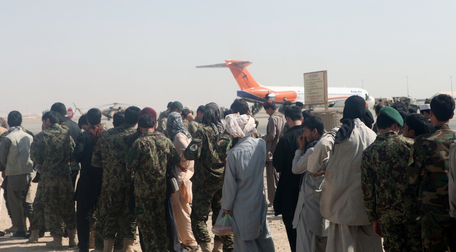 More than 100 Afghan National Army soldiers with the 215th Corps as well as Afghan civilians stand waiting to board an aircraft aboard Camp Bastion, Helmand province, Afghanistan, Sept. 27, 2014. The soldiers and civilians are planning to travel to Kabul for a rest and relaxation period with their families. (U.S. Marine Corps photo by Cpl. Cody Haas/ Released)