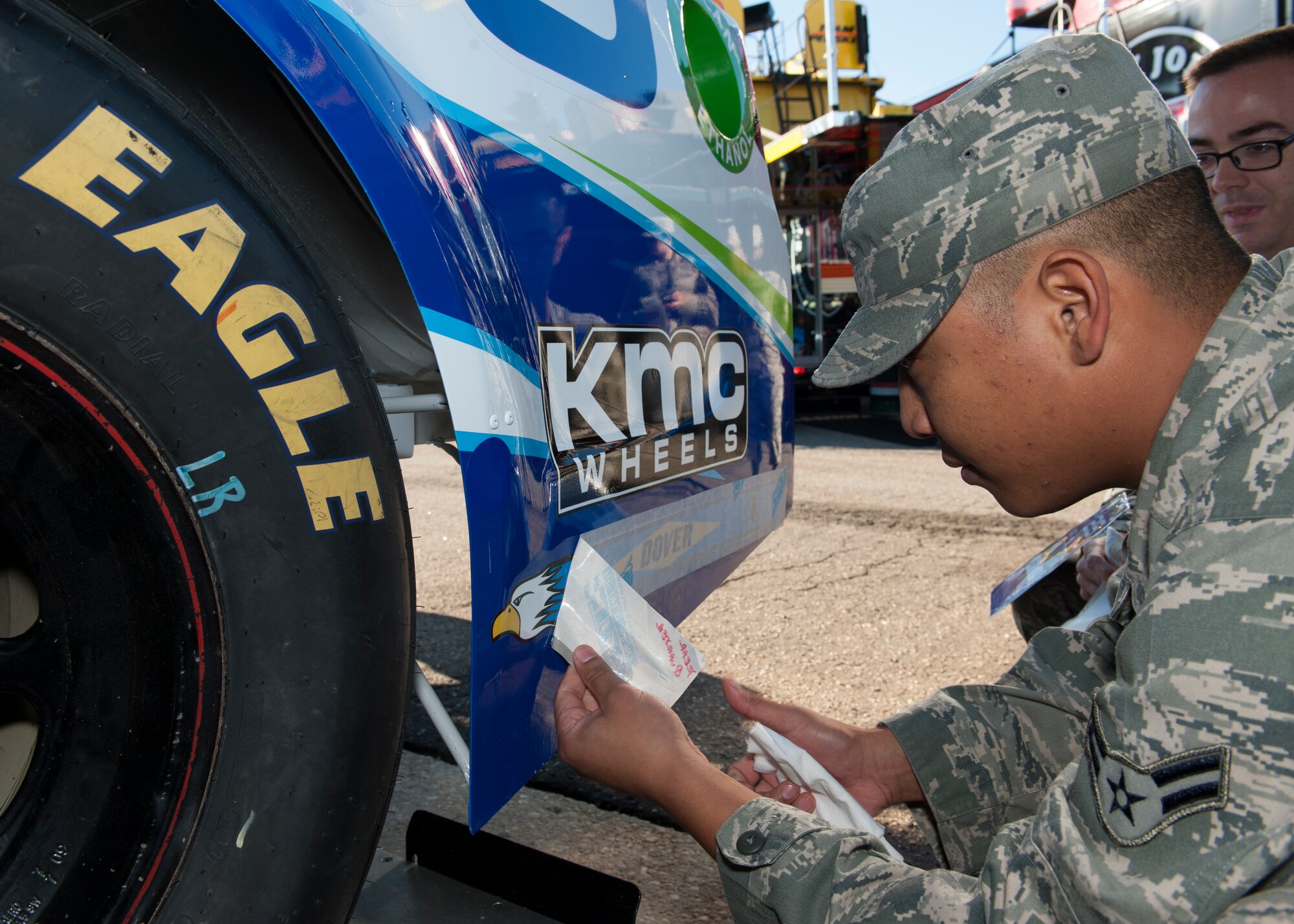Airman 1st Class Loren Genao applies a Dover Air Force Base tail flash decal to the Germain Racing No. 13 GEICO Chevy SS Sept. 26, 2014, at Dover International Speedway in Dover, Del. This tail flash and two others were placed on the car to thank the Airmen at Dover AFB, Delaware for their service. Genao is an aircraft structural maintainer with the 436th Maintenance Squadron. (U.S. Air Force photo/Airman 1st Class Zachary Cacicia)
