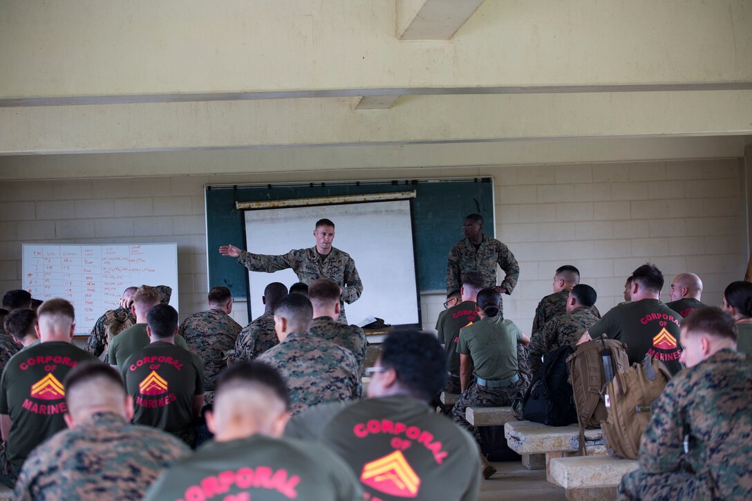Sgt. Michael J. Elgaen, standing left, briefs Marines Sept. 23 prior to their completion of a land navigation course at the Jungle Warfare Training Center, Camp Gonsalves. The participants learned how to use and apply terrain association in conjunction with traditional compass and distance measuring methods to find their assigned points. The Marines are with various units across III Marine Expeditionary Force. (U.S. Marine Corps photo by Lance Cpl. Ryan C. Mains/Released)