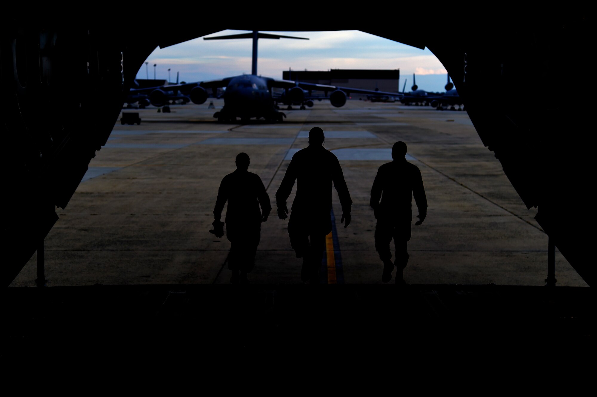 JOINT BASE MCGUIRE-DIX-LAKEHURST, N.J. - Three Airmen from the 621st Contingency Response Wing walk out of a Globemaster III C-17 from Joint Base Charleston, N.C., after loading a Hard-side Expandable Light Air-Mobile Shelter (HELAMS) here, Sept. 29, 2014. The HELAMS will be used by the 621 CRW in West Africa in support of Operation UNITED ASSISTANCE in response to the Ebola virus disease outbreak. The CRW is highly-specialized in training and rapidly deploying personnel to quickly open airfields and establish, expand, sustain, and coordinate air mobility operations. From wartime taskings to disaster relief, the CRW extends Air Mobility Command's reach in deploying people and equipment around the globe. (U.S. Air Force photo by Staff Sgt. Gustavo Gonzalez/Released)