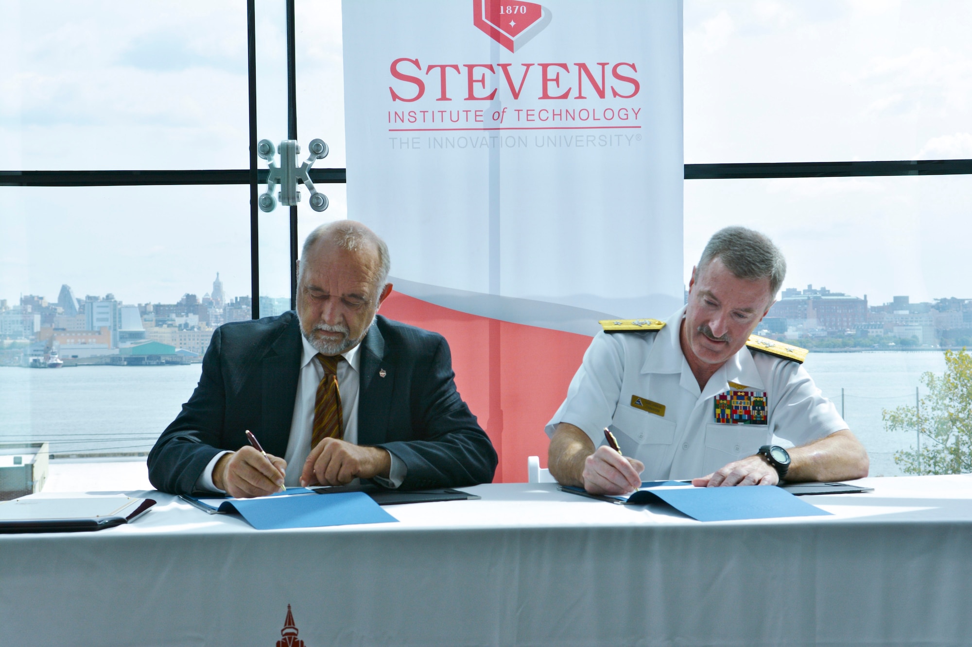 Dr. George Korfiatis, Stevens Institute of Technology Provost and University vice president, and Rear Adm. Mark Darrah, Naval Air Warfare Center, Aircraft Division commander, sign an educational partnership agreement between Stevens and the U.S. Navy at a ceremony on the Stevens campus in Hoboken, N.J., Sept. 24, 2014. (Courtesy photo)