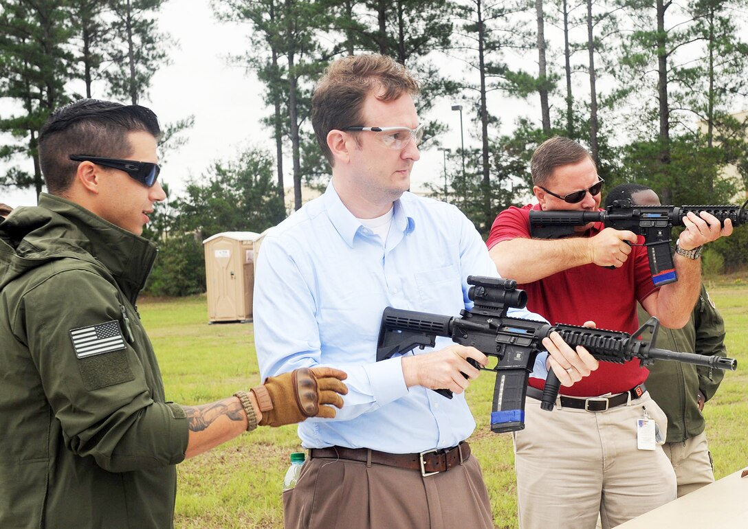 A member of the 5th Combat Communications Group assists Jason Murphy, military legislative assistant for Congressman Tom Graves, and Kevin Reigurt, chief of staff for Congressman Andrew Harris, as they fire practice rounds during their visit to the installation Sept. 25. (U. S. Air Force photo by Tommie Horton)