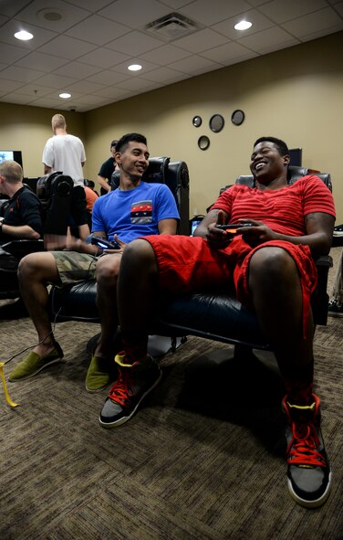 U.S. Air Force Airman 1st Class Yazin Singayo, 23d Civil Engineer Squadron heavy equipment operator, left, laughs with Senior Airman Shannon Winthrop, 23d Communications Squadron network administrator, as they compete in a video game tournament Sept. 28, 2014, at Moody Air Force Base, Ga. The tournament was hosted by the base dormitory Council to help Airmen develop social networks and boost morale. (U.S. Air Force photo by Senior Airman Sandra Marrero/Released)
