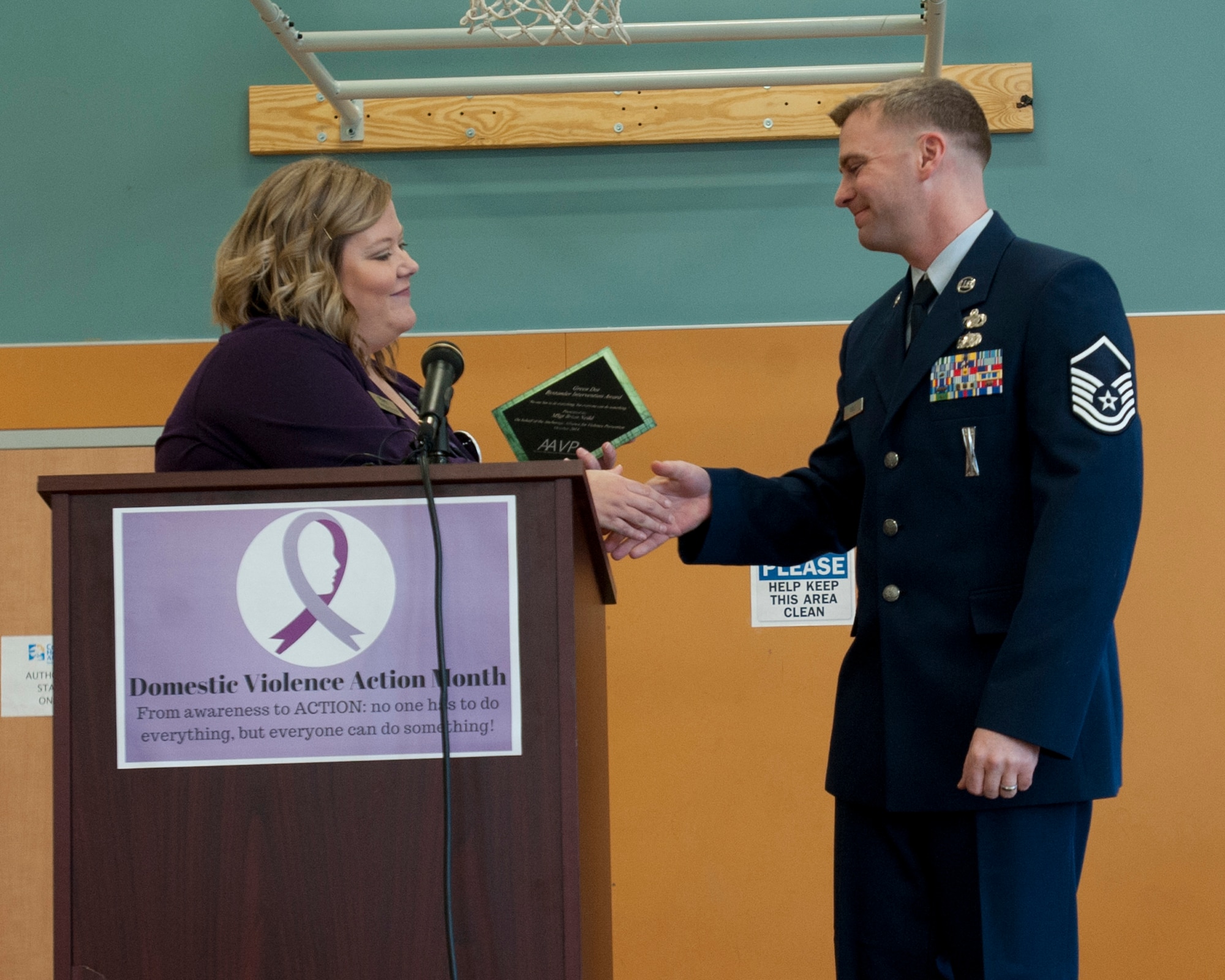 Melissa Emmal presents Alaska National Guard Master Sgt. Brian Neild with the Green Dot Bystander Award during the Domestic Violence Prevention Month opening ceremony on Oct. 1, 2014. Emmal is the deputy director for the Abused Women’s Aid in Crisis. Neild was given the award for acting during a case of domestic violence. (U.S. Air Force photo/Staff Sgt. Robert Barnett)