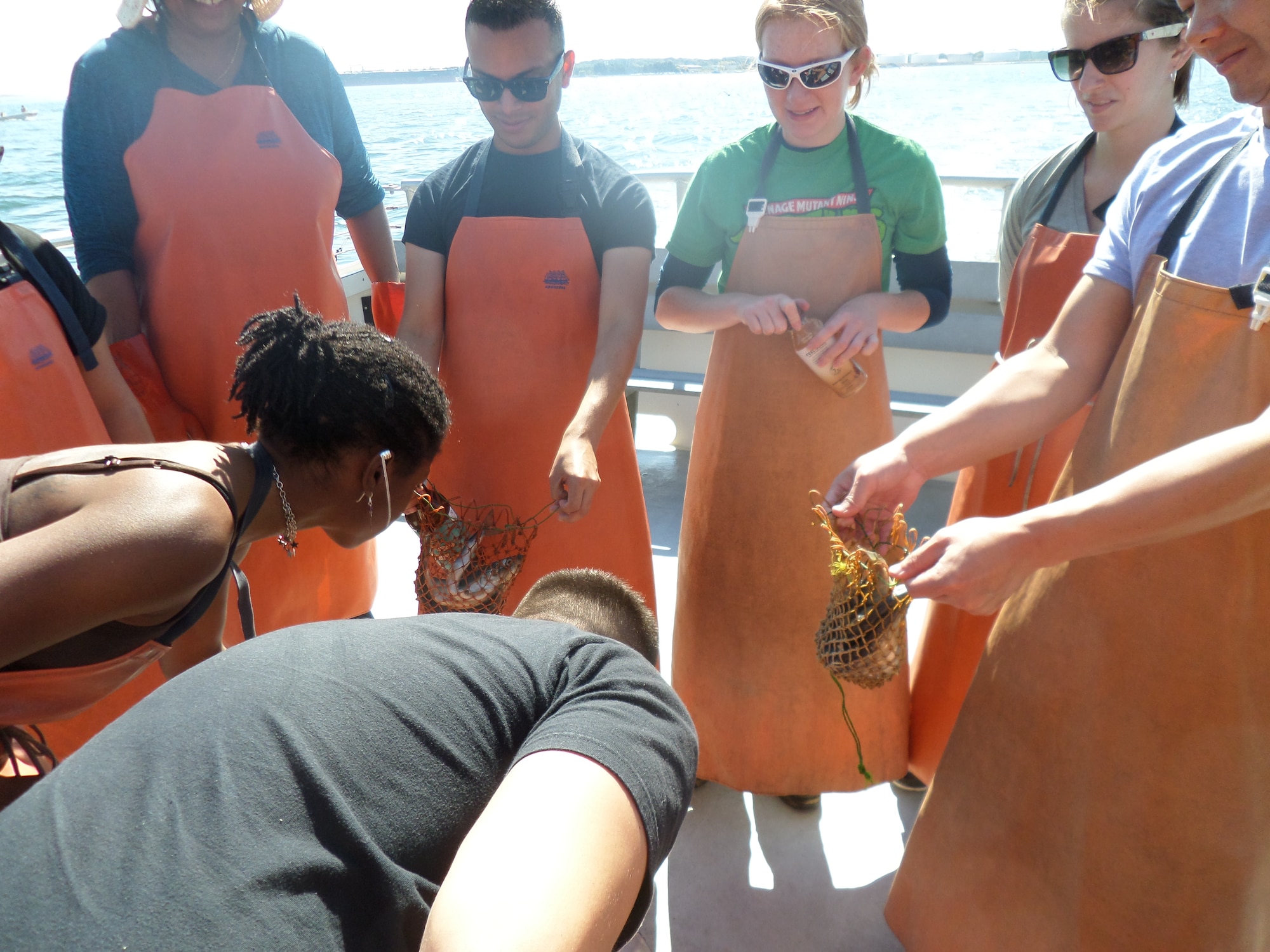 Decked out in industrial strength rubber gloves and aprons, Airmen fill bait bags with fish during the Junior Force Council's Lobstering Excursion to Portland, Maine, Sept. 27. The social event brought Airmen across various offices together and gave them the opportunity to get hands-on during a lobstering trip. (U.S. Air Force photo by Jeff Price)