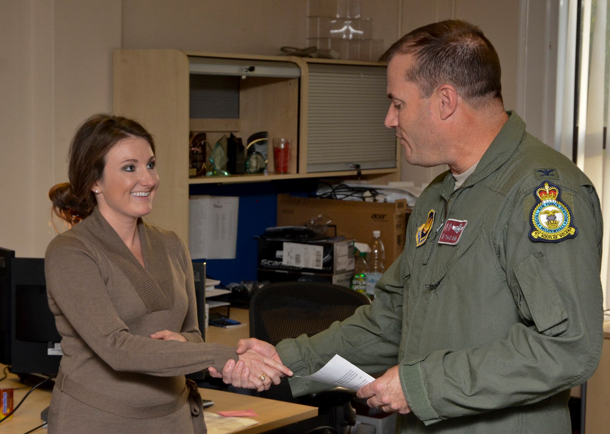 U.S. Air Force Col. Kenneth T. Bibb Jr., right, 100th Air Refueling Wing commander, gives a coin to Andrea Flores, 100th Comptroller Squadron budget analyst from Williamsburg, Iowa, Sept. 30, 2014, on RAF Mildenhall, England. Bibb recognized Flores for her hard work allocating funds for the end of year close out. (U.S. Air Force photo/Staff Sgt. Micaiah Anthony/Released)