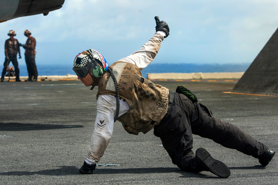 U.S. Navy Petty Officer 3rd Class Justin Knappenberger signals that an F/A-18F Super Hornet is ready to launch from the flight deck of the aircraft carrier USS Carl Vinson in the Pacific Ocean, Sept. 22, 2014. Knappenberger is an aviation electronics technician. Knappenberger is assigned to Strike Fighter Squadron 22.