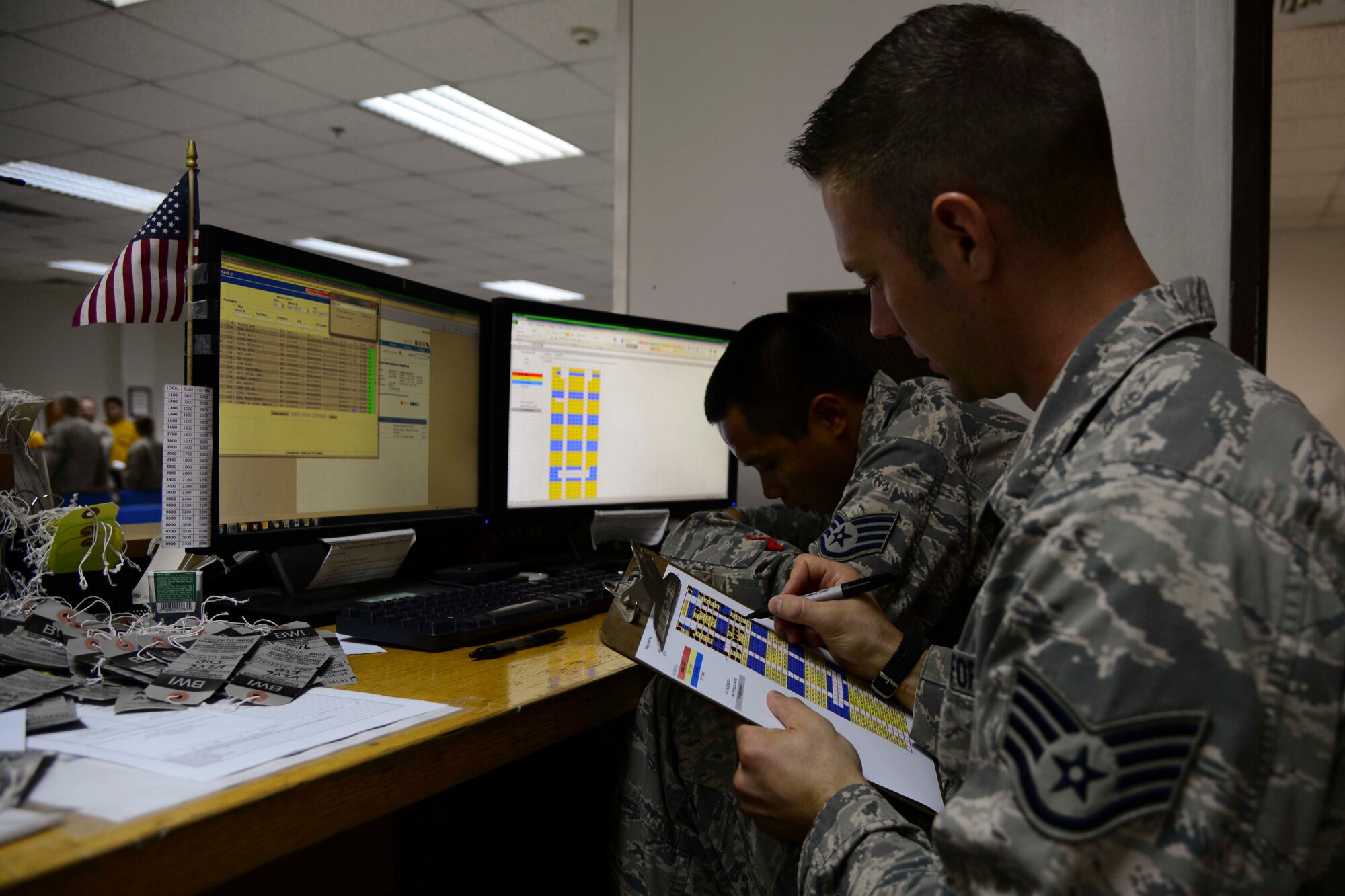U.S. Air Force Staff Sgts. Marvin Villegas, left, and Jason Golden, 8th Expeditionary Air Mobility Squadron passenger service supervisors, validate seat assignments at Al Udeid Air Base, Qatar, Oct. 1, 2014. The validation ensures that all passengers have seat assignments and there are no double bookings. (U.S. Air Force photo by Staff Sgt. Ciara Wymbs)