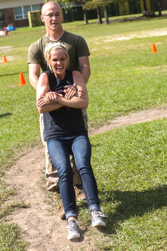 Lance Cpl. Andrew Lewis, a bulk fuel specialist with 8th Engineering Support Battalion, drags his wife, Catherine Lewis, while conducting the movment under fire portion of the Combat Fitness Test during the Jane Wayne day aboard Camp Lejeune, N.C., Sept. 30, 2014. The Kalamazoo, Mich., couple used each other as training partners in this event to build a better relationship between each other. Jane Wayne day is designed to show spouses a few of the jobs their Marines perform and to strengthen the bond between unit and family. (U.S. Marine Corps photo by Cpl. Michael Dye / Released)