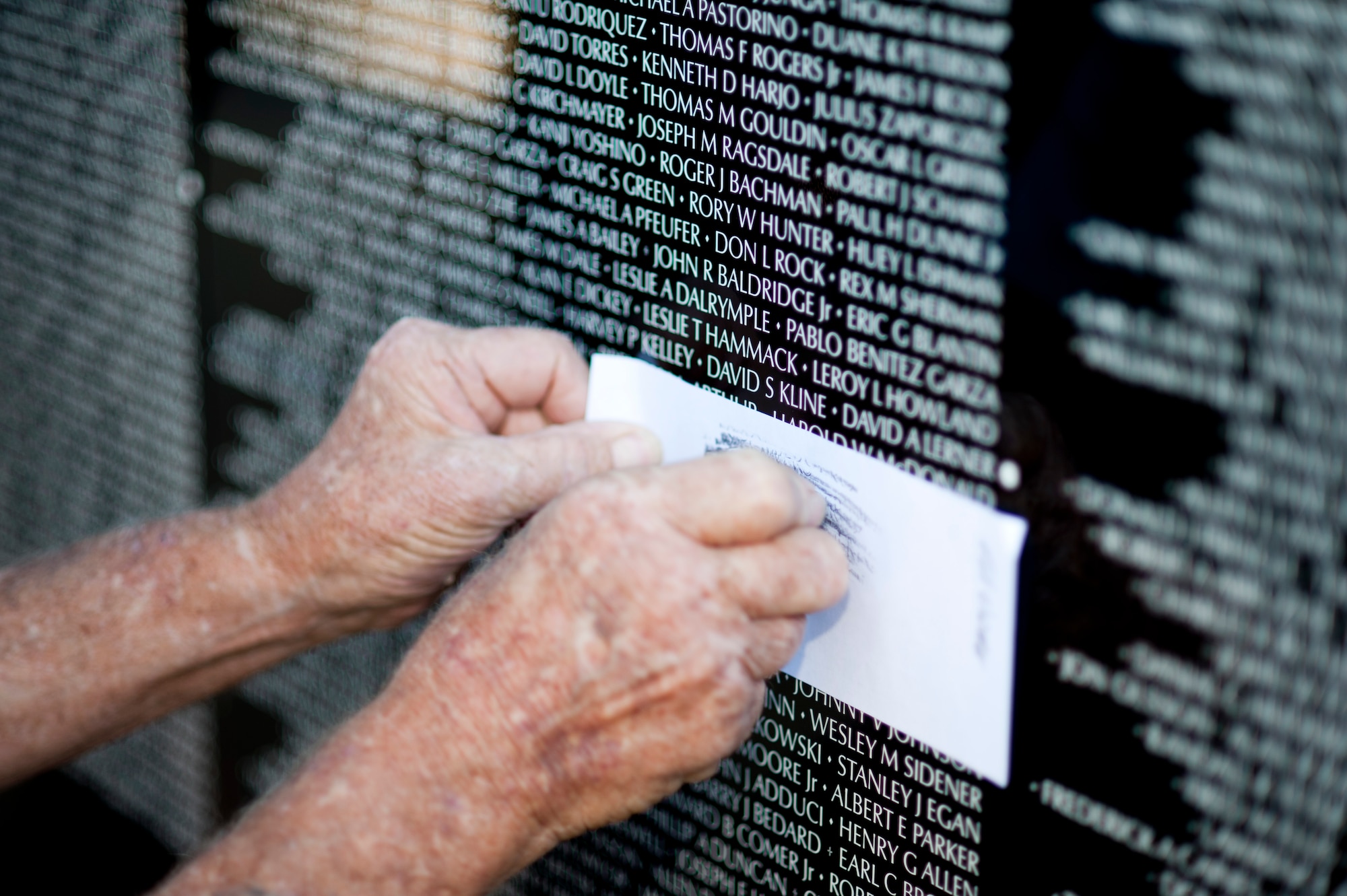 Ed Doughty, U.S. Navy Vietnam veteran, copies a name from "The Moving Wall," a Vietnam veterans memorial wall, in Goodyear, Arizona, Oct. 03, 2014. Inscribed on the black granite walls are the names of more than 58,249 men and women who gave their lives or remain missing. (U.S. Air Force photo by Staff Sgt. Staci Miller) 